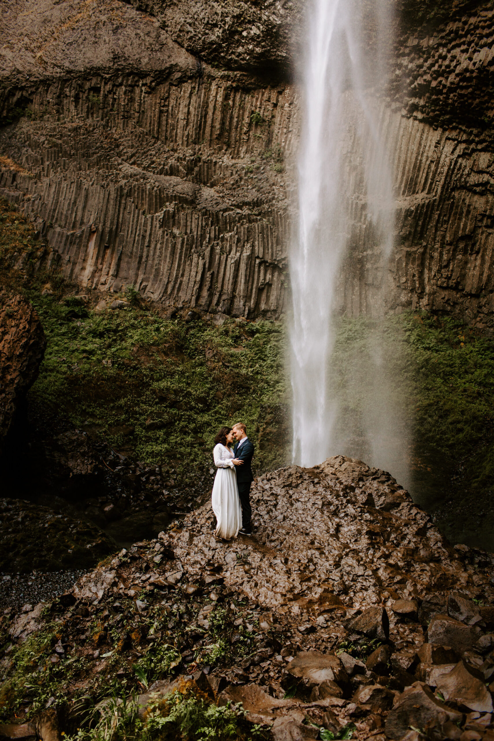 elopement-travel-couple-embracing-on-rocks-near-beautiful-waterfall.jpg